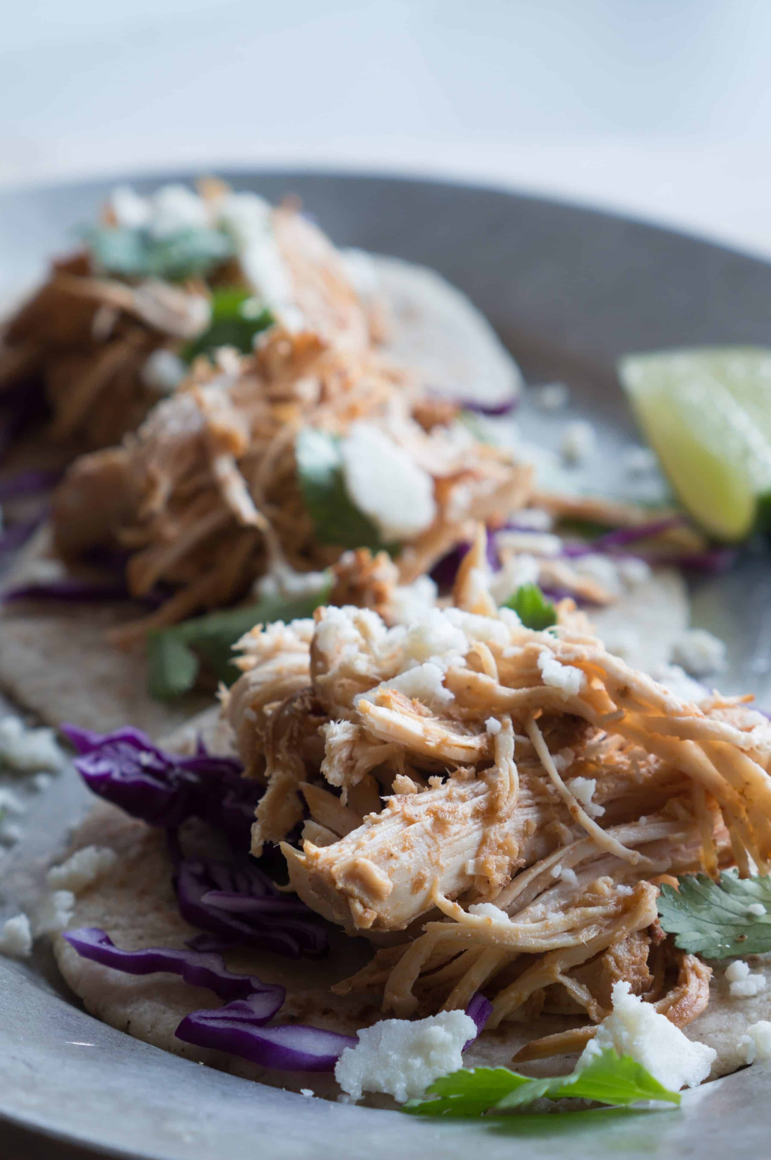 Shredded Chicken Street Tacos – We love this gluten-free recipe for Shredded Chicken Street Tacos! It is so simple to throw together as a weeknight dinner or for a big get-together. Put your slow cooker to work to turn lean, protein-packed chicken breasts into these tasty little tacos. Top them with fresh cilantro, crumbled cotija cheese, crunchy cabbage slaw, spicy salsa, creamy guacamole, or a squeeze of lime juice. Deck them out however you please! ♥ | freeyourfork.com