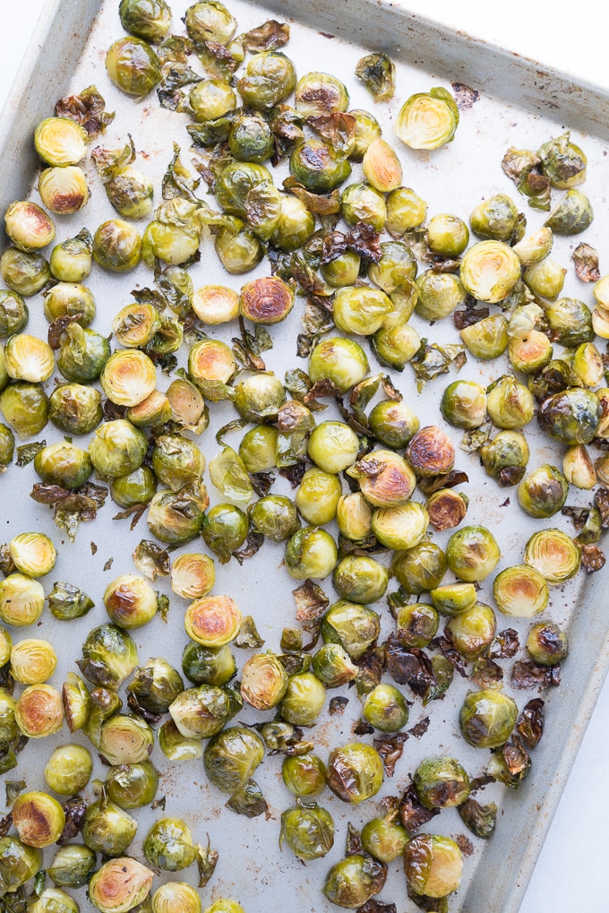 top down view of roasted brussels sprouts on a sheet tray with salt and pepper