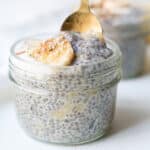Glass jars of banana chia pudding with a gold spoon being dipped in.
