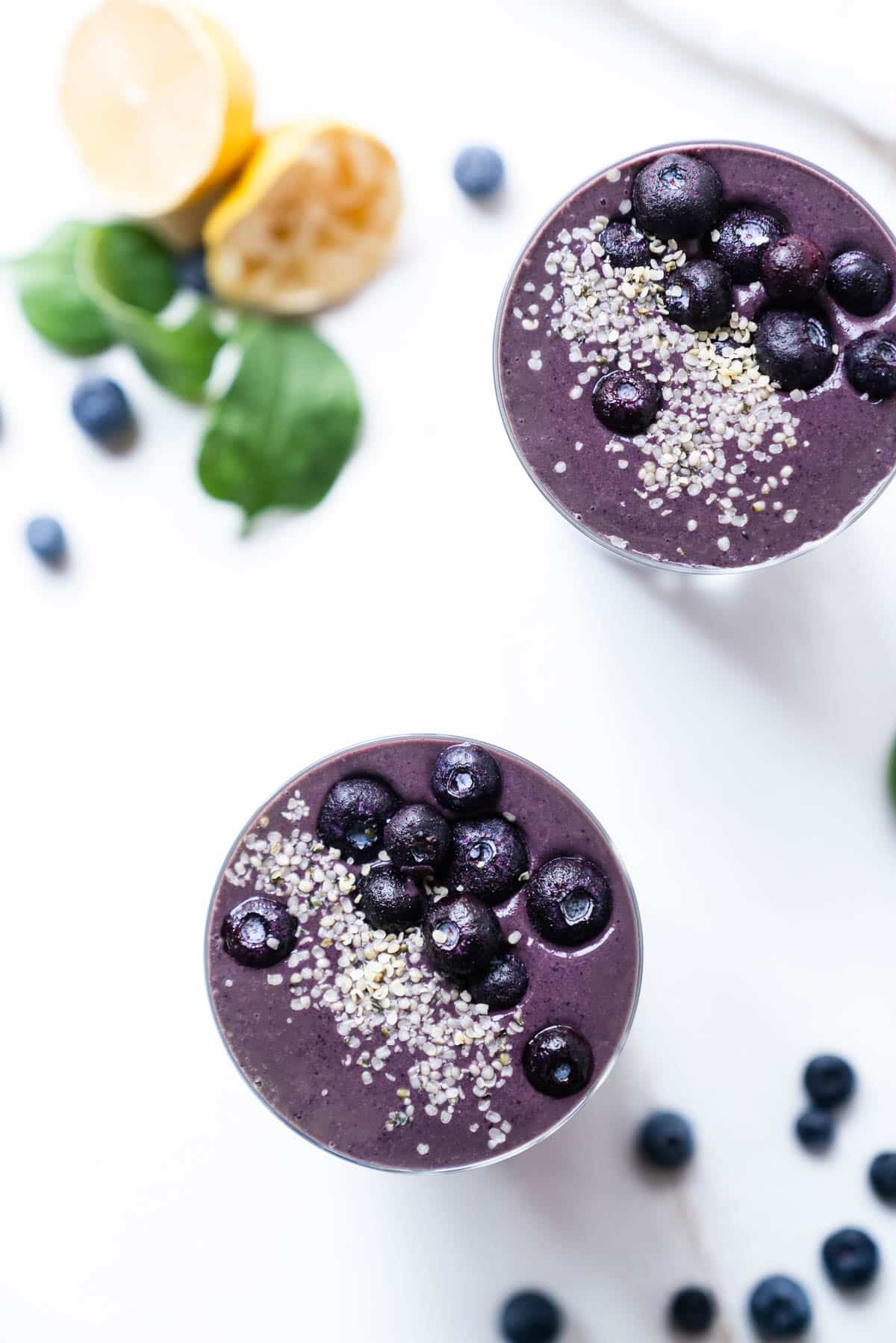 Close up of two smoothies topped with fresh berries and hemp seeds.