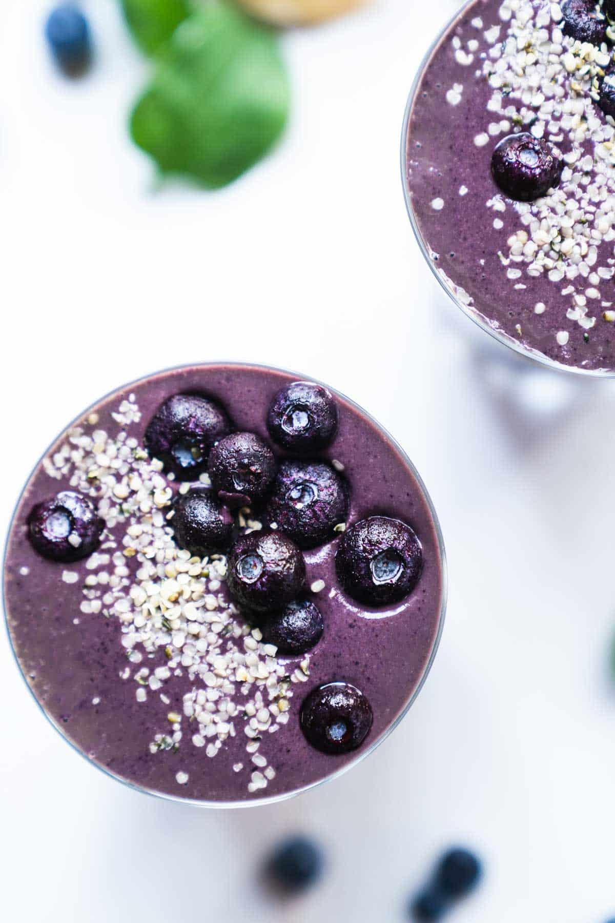 Close up of two smoothies topped with fresh berries and hemp seeds.