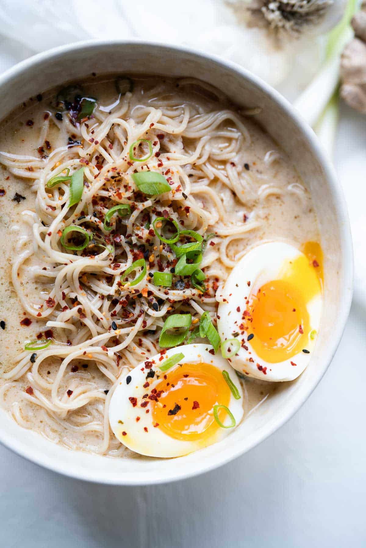 Overhead shot of a white bowl filled with gluten free ramen soup and topped with a soft boiled egg.