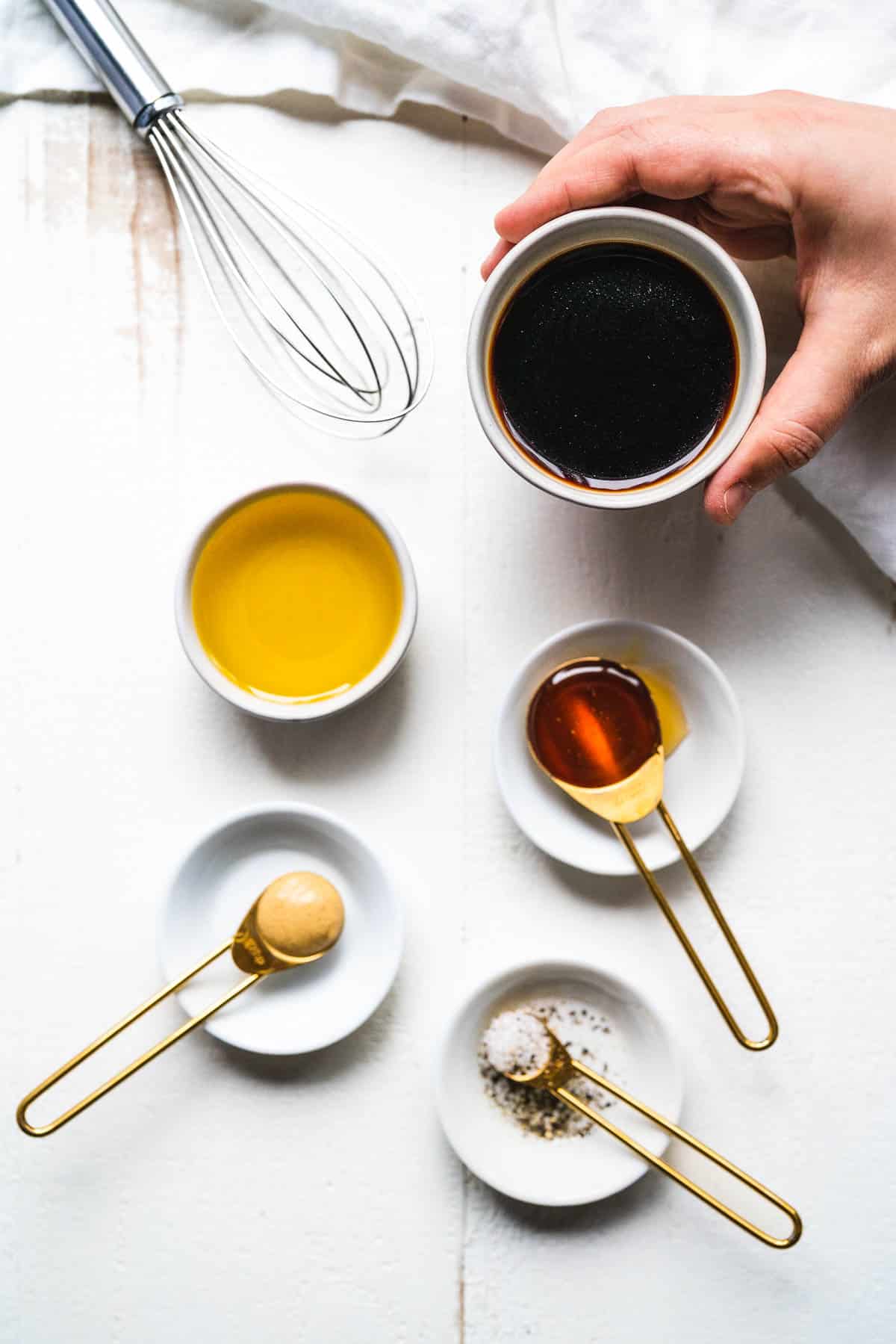 Ingredients for honey balsamic vinaigrette on a white table.