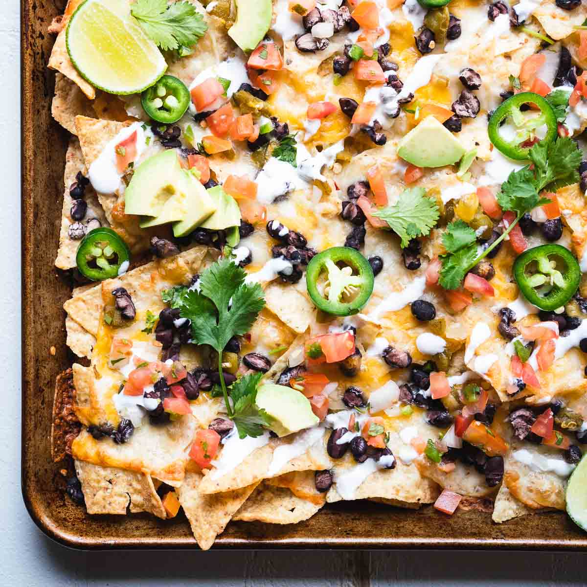 Overhead shot of a tray of oven baked nachos loaded with toppings.