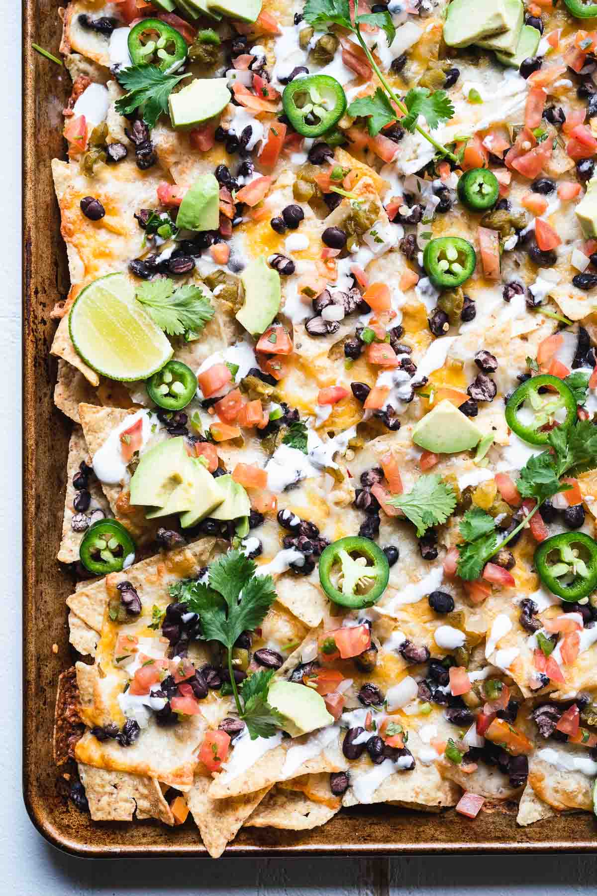 Overhead shot of a tray of oven baked nachos loaded with toppings.