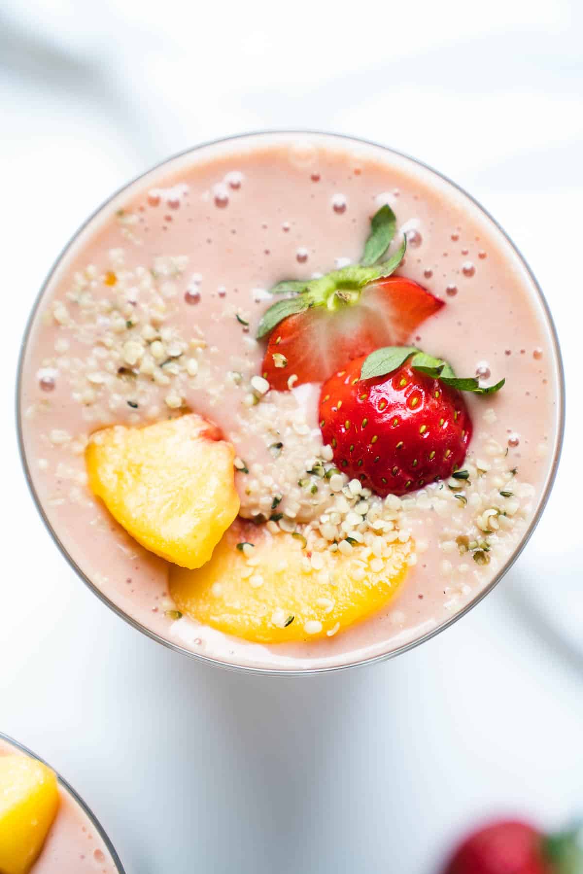 Closeup of a smoothie topped with fresh fruit and hemp seeds.