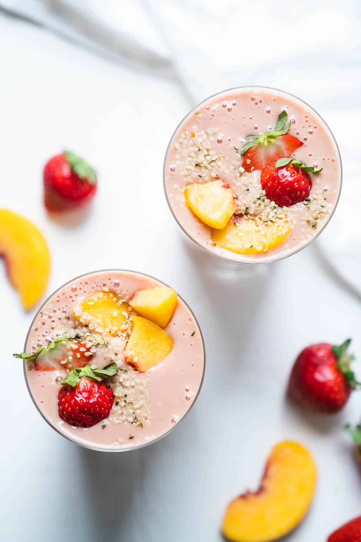 Overhead shot of two glasses filled with strawberry peach smoothies.