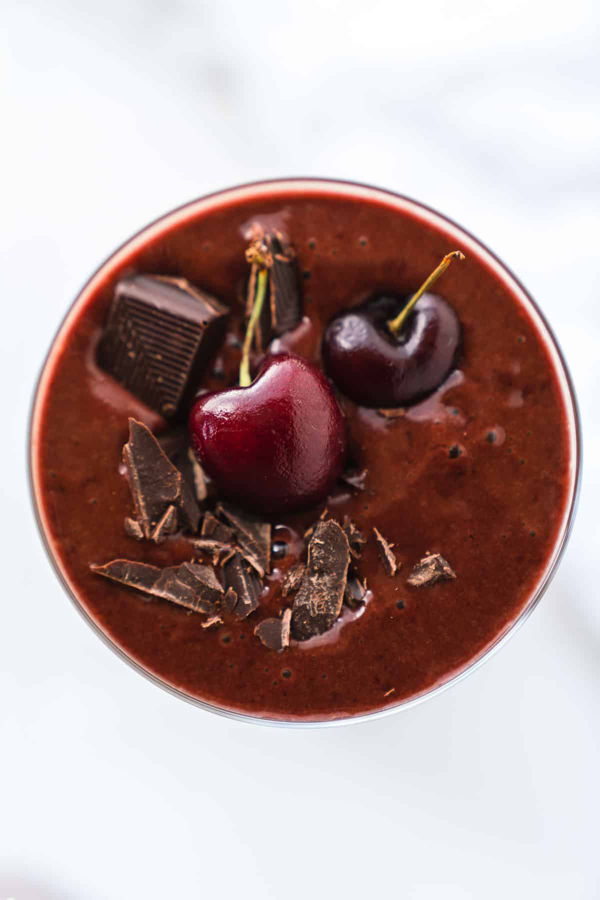 Overhead shot of a chocolate cherry smoothie topped with fresh fruit and chocolate shavings.