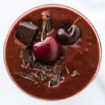 Overhead shot of a chocolate cherry smoothie topped with fresh fruit and chocolate shavings.
