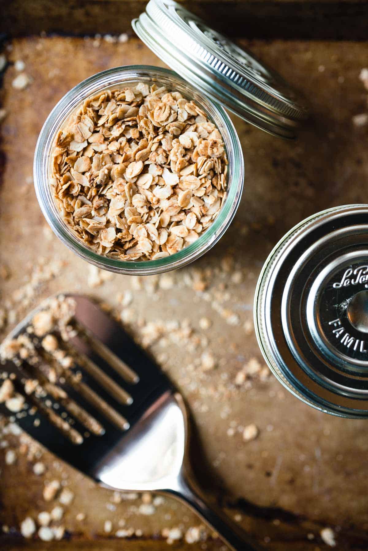 Overhead shot of a glass jar filled with nut free granola with a gold spatula on the side.