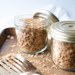 Two jars of nut free granola with a gold spatula in the front.
